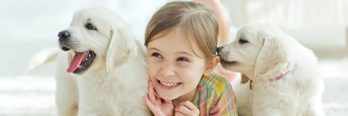 A young girl and her pet puppies on a carpet in Longview cleaned with pet and child-friendly products.